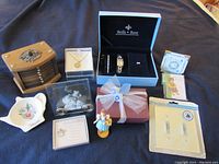 View of mixed jewelry items and related gift/decor items on a blue cloth background.