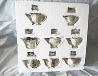 Foam packaging showing nine white Lenox ceramic tea pots with lids arranged in protective slots.