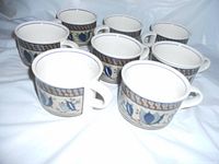 Set of eight blue Mikasa Intaglio ceramic cups showing front and side views with blue floral and geometric decorative band work.