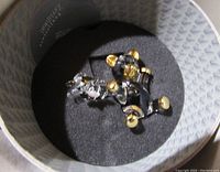 Crystal bears placed on a black foam insert inside a round box, showing their size and gold detailing