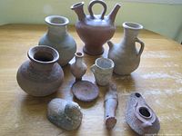 Photo showing 10 vintage Chirique pottery pieces including pots, vases, a small figurine, and an oil lamp, arranged on a wooden table.