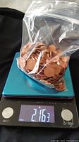 Clear plastic bag filled with Canadian pennies placed on a digital scale showing a weight of 2.163 pounds.