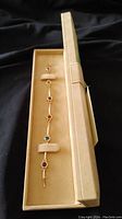 Full view of gold bracelet in presentation box showing multicolor stones