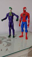Photo of Spider-Man and Joker action figures standing upright on a flat surface.