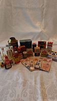 Collection of assorted vintage household items including tins, bottles, and small packages on a white patterned surface.
