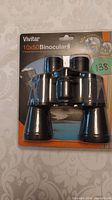 Front view of Vivitar 10x50 binoculars in original sealed packaging, showing product and brand name.