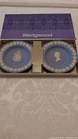 Two blue jasperware comport plates with white relief designs in Wedgwood purple box