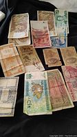 Photo showing a variety of world banknotes laid out on a flat surface for identification, featuring different colors and designs.