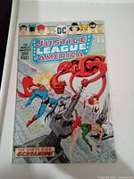 Front cover of Justice League of America comic book issue #129 showing DC superheroes battling a large mechanical creature.