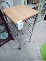 Full view of metal kitchen caddy with wood top and wire basket drawers on wheels