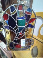 Photo showing full front view of the original stained glass window panel with various colored glass sections and lead framing.