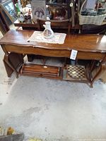 Photo of the wooden hall table showing front view with two side cabinet doors open, central drawer open revealing storage inside. Items on top and underneath table not included in sale.