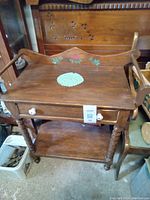 Front view of wooden wash stand showing drawer, shelf and decorative back panel with painted flowers.