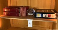 Shelf with a group of vintage books, a binder labeled with '60s' and '70s', and an 8-inch glass ball in the center.