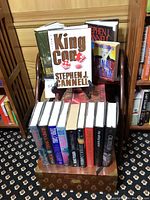 Display showing Stephen J. Cannell books arranged on a small wooden shelf above a wooden cigar box with brass accents