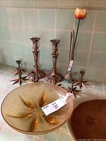 Full lot with candlestick holders, yellow bowl, and tulip vase on countertop with tiled wall background