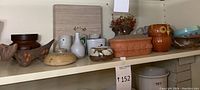 Shelf with assorted animal themed ceramics and terra cotta decor including owl mug, vase, small pots, and dried flower arrangement