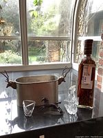 Photo showing all items including metal planter, glass bottle with peppers, glass vase, and metal horse figurine on countertop.