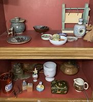 Wide shelf overview showing assorted decorative items including ceramic bowls, brass deer figure, small wooden holder