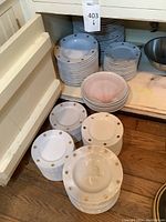 Stacked white plates with gold star patterns and pink shell design plates visible.