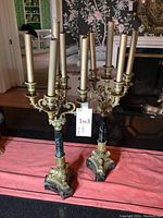 Overview of both candelabras on red cloth with candles inserted