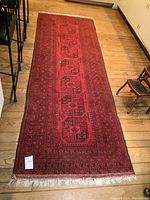 Full view of the red and black runner rug revealing size, overall pattern and fringed ends.