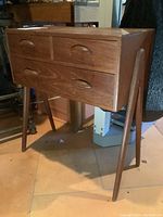 Front view of wooden two-drawer side table showing drawer fronts and tapered legs
