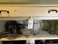 Shelving featuring crystal bowl, pottery and glass vases grouped together