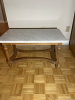 Full front view of coffee table showing white marble top and wooden base with turned legs.