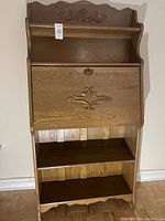 Front view of solid oak secretary's desk with carved details and a closed fold-down panel.