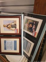 Two sets of solid wood picture frames, one reddish-brown set and one dark brown set, both 11 in x 14 in, still in packaging with inserts