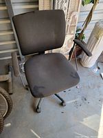 Full view of the black office chair showing the seat, backrest, and armrests with visible cosmetic wear.