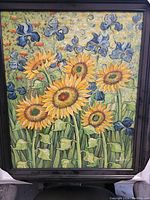 Full view of the framed oil painting showing sunflowers and blue irises in a field with textured background.