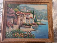 Full view of the oil on canvas painting showing a lakefront village scene with colorful buildings, flowers, and water.