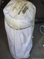 Rolled-up rug in white woven packaging