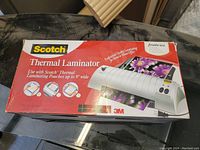 Closed box showing Scotch Thermal Laminator branding and description suitable for laminating pouches up to 9 inches wide.