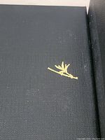 Close-up of black gift box lid with small gold decorative emblem resembling a branch or twig.