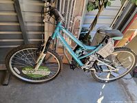 Blue and white women's Huffy bike showing front and rear wheels and frame, placed indoors.