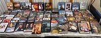 Overview of the large collection of DVDs spread on a surface showing many titles and colorful covers.
