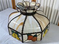 Full view of vintage stained glass hanging lamp with fruit design including yellow and orange fruits and dark metal leading.
