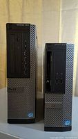 Two Dell Optiplex tower computers side by side showing full front panel views.