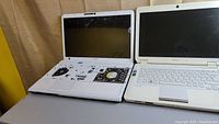 Two Sony Vaio laptops on a table, one missing keyboard and internal components exposed, other intact
