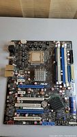 Top-down image showing entire Asus motherboard including PCI slots, RAM slots and CPU socket with Intel CPU installed.