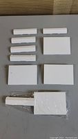 Ten white plastic doors and panels laid out flat, visible front side shown in image. Includes several narrow door pieces and rectangular panels.