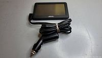 Magellan GPS device with attached power/mic cable, showing front screen and coiled cable with car power adapter plug.