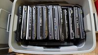 Top view of Rubbermaid container filled with Lenovo laptops vertically stacked showing side ports and various laptop thicknesses.