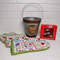 Photo of lot items including tin Snowball Farm pail, kitchen linens, and snowman napkin rings arranged together