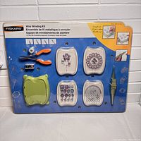Full view of Fiskars Wire Winding Kit in original sealed packaging, showing pliers, wire spools, winding tool, and bead trays on blue backing card.
