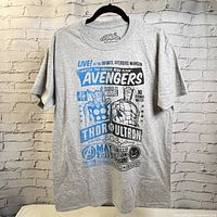 Full front view of gray Marvel Avengers T-Shirt on hanger against brick wall, showing graphic print of Thor and Ultron with Avengers branding.