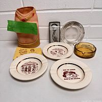 Photo shows vintage naughty adult-themed bar lot items including four ceramic ashtrays with adult humor designs, torso-shaped ceramic decoration, Golden Nugget amber glass ashtray, clear glass ashtray, and metal keychain in original packaging.